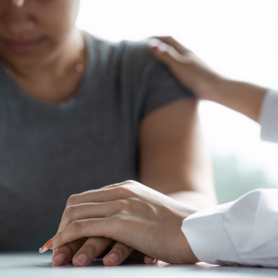 National suicide prevention month: what your practice can do to help prevent suicide 10 A doctor holding her hand on a patient's hand and shoulder, comforting her, representing national suicide prevention month