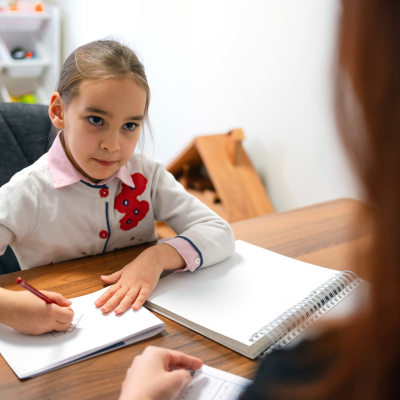 How to help a child with test anxiety 5 Child writing while adult observes attentively, representing how to help a child with test anxiety